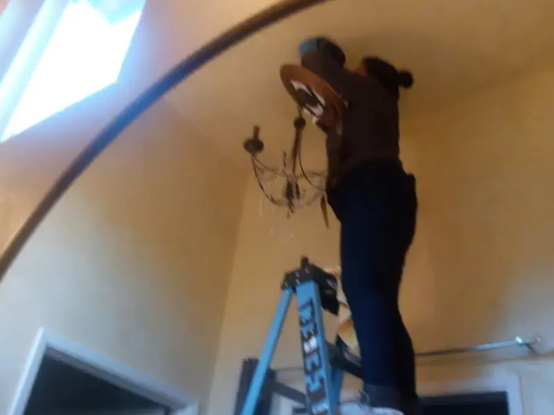 Electrician installing a chandelier in a Anna residence